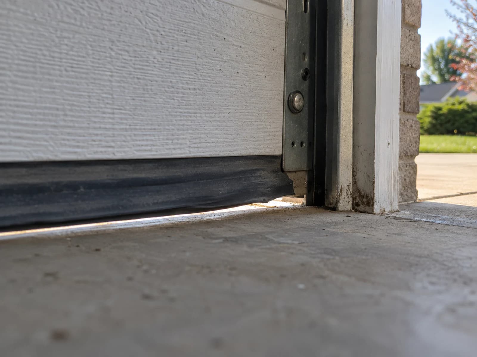 Worn garage door bottom seal with a gap at the corner large enough for a mouse.